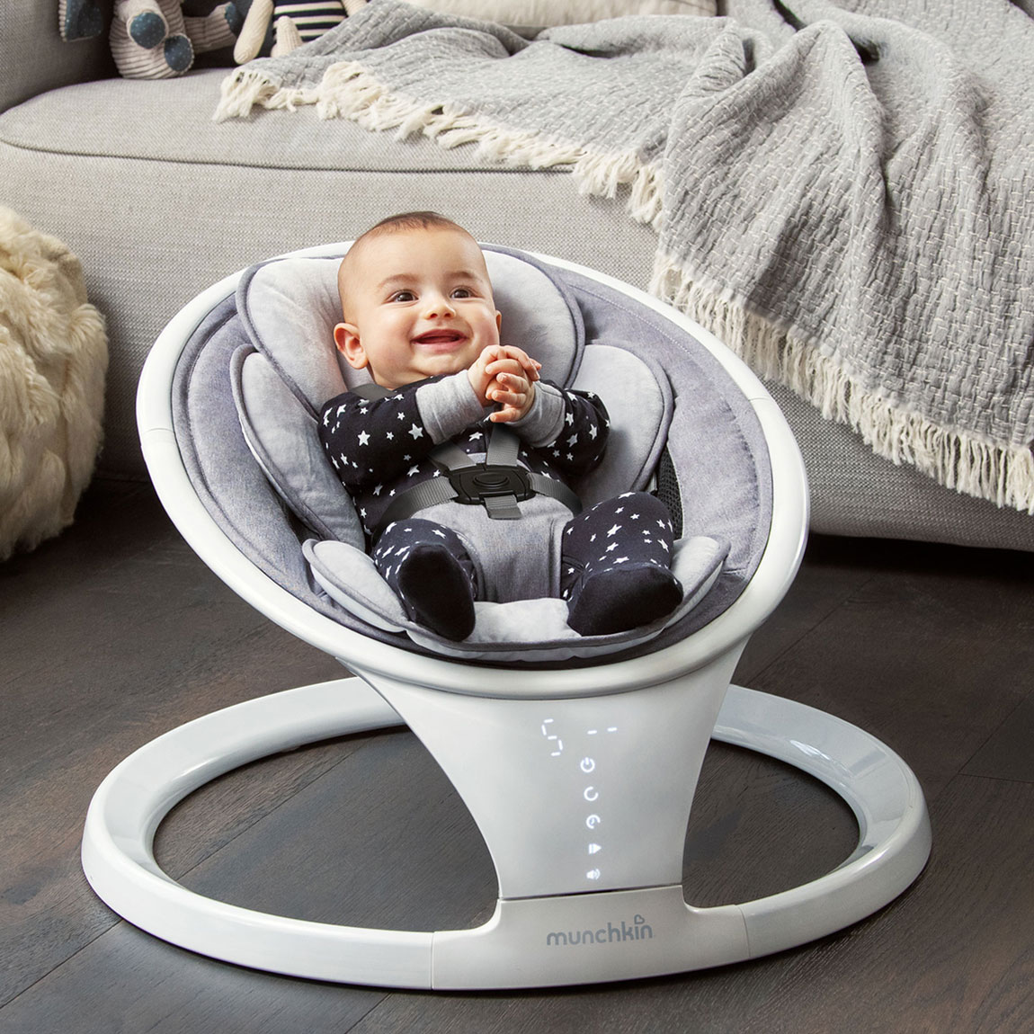 A smiley baby sitting in a Munchkin Baby Swing